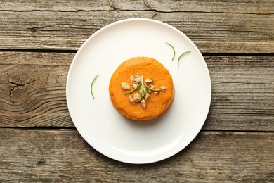 Photo of Plate with tasty mashed sweet potato, rosemary and walnuts on wooden table, top view