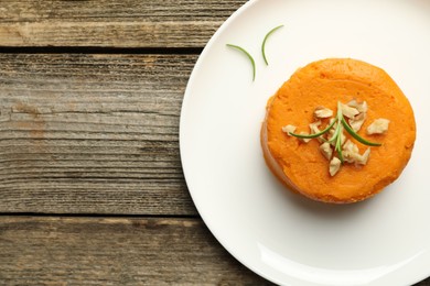 Photo of Plate with tasty mashed sweet potato, rosemary and walnuts on wooden table, top view. Space for text