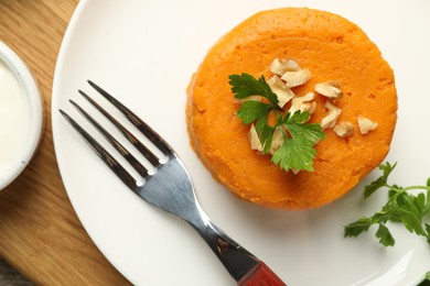 Photo of Plate with tasty mashed sweet potato, parsley and walnuts on wooden table, top view