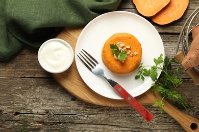 Photo of Tasty mashed sweet potato, parsley and walnuts served with sauce on wooden table, flat lay