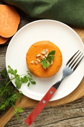 Photo of Tasty mashed sweet potato, parsley and walnuts served on wooden table, flat lay