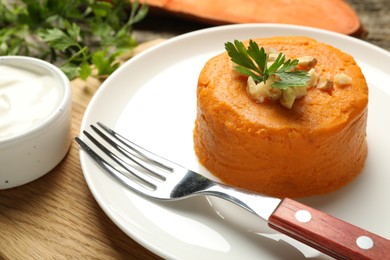 Photo of Tasty mashed sweet potato, parsley and walnuts served with sauce on wooden table, closeup