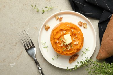 Photo of Tasty mashed sweet potato, butter, thyme and walnuts served on grey textured table, flat lay