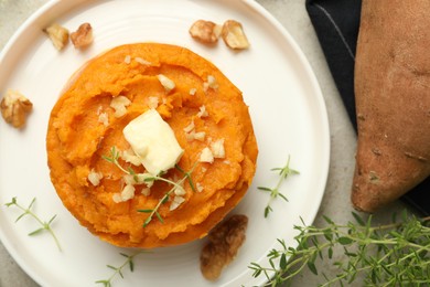 Photo of Tasty mashed sweet potato, butter, thyme and walnuts on grey table, flat lay