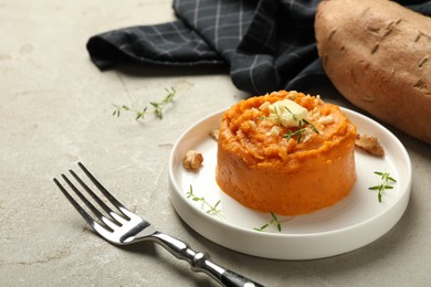 Photo of Plate with tasty mashed sweet potato, butter, thyme and walnuts on grey textured table, closeup