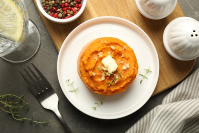 Photo of Tasty mashed sweet potato, butter, thyme and walnuts served on grey textured table, flat lay