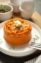 Photo of Plate with tasty mashed sweet potato, butter, thyme and walnuts served on table, closeup