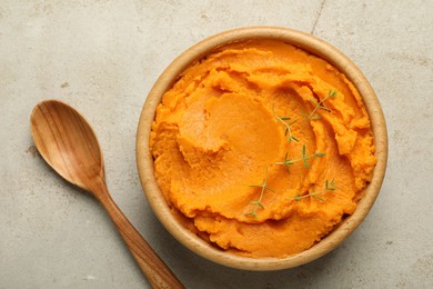 Photo of Tasty mashed sweet potato and thyme in bowl on grey textured table, top view