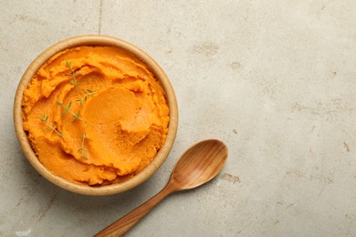 Photo of Tasty mashed sweet potato and thyme in bowl on grey textured table, top view. Space for text