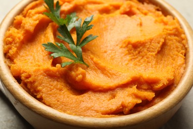 Photo of Tasty mashed sweet potato and parsley in bowl on table, closeup