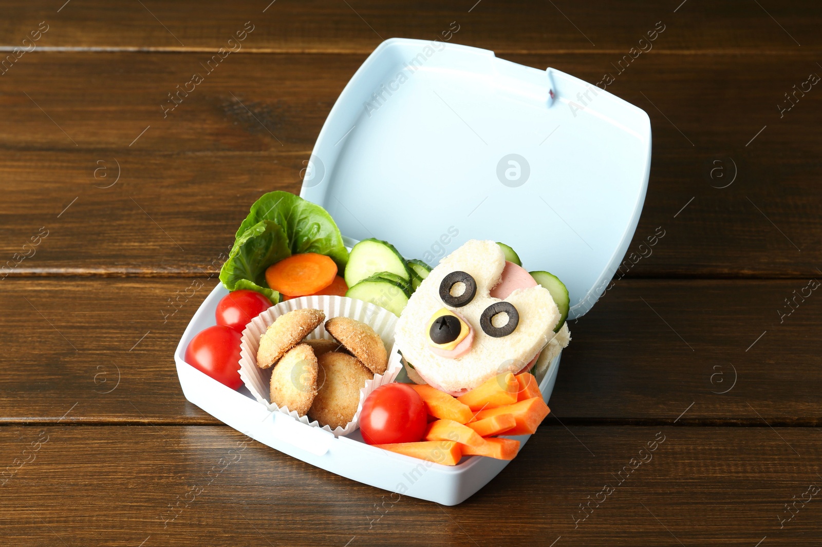 Photo of Lunch box with sandwich, fresh vegetables and cookies on wooden table