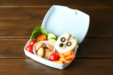 Photo of Lunch box with sandwich, fresh vegetables and cookies on wooden table