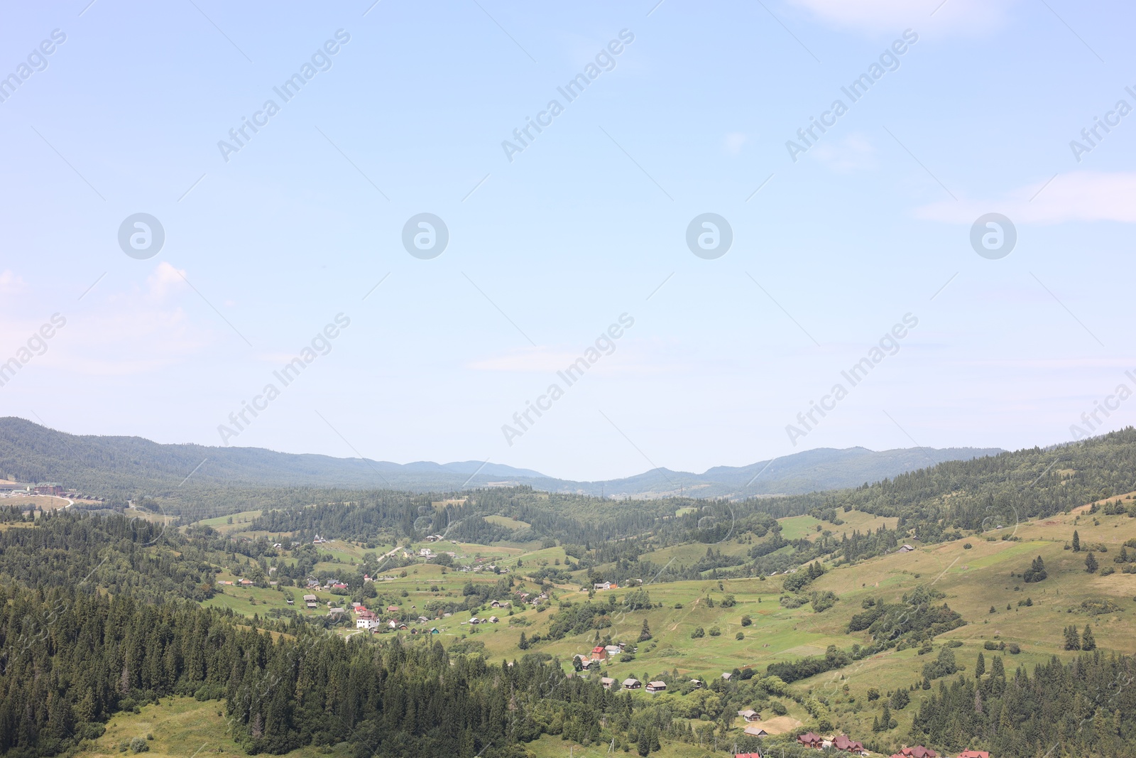 Photo of Beautiful trees and houses in mountains under blue sky