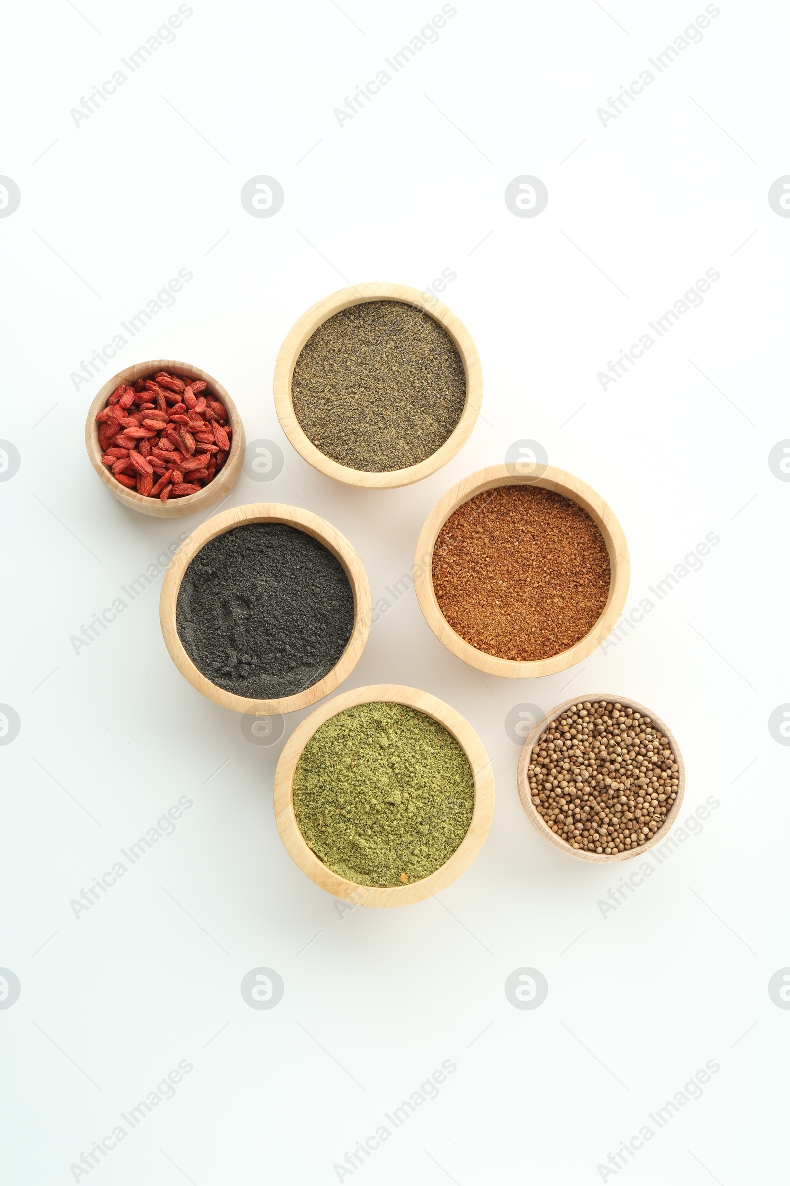 Photo of Different superfood powders and goji berries in bowls on white background, flat lay