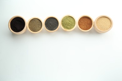 Different superfood powders in bowls on white background, flat lay. Space for text