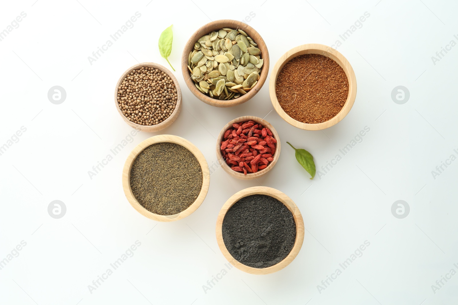 Photo of Different superfood powders, pumpkin seeds and goji berries in bowls on white background, flat lay