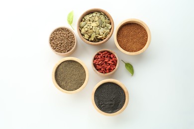 Photo of Different superfood powders, pumpkin seeds and goji berries in bowls on white background, flat lay