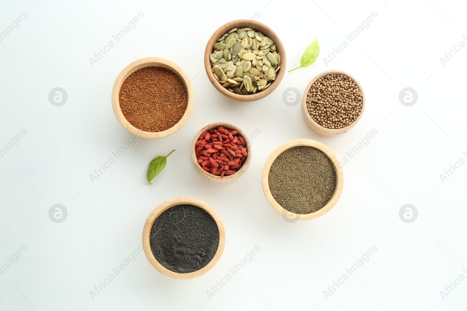 Photo of Different superfood powders, pumpkin seeds and goji berries in bowls on white background, flat lay