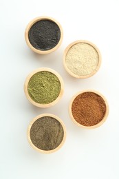 Different superfood powders in bowls on white background, flat lay