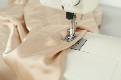 Sewing machine with beige fabric on table, closeup