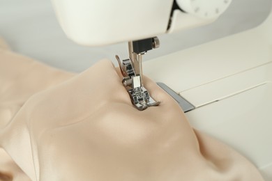 Sewing machine with beige fabric on table, closeup