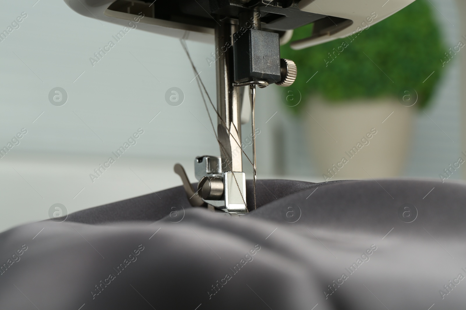 Photo of Sewing machine with gray fabric indoors, closeup