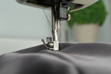 Sewing machine with gray fabric indoors, closeup