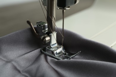 Sewing machine with gray fabric on light background, closeup