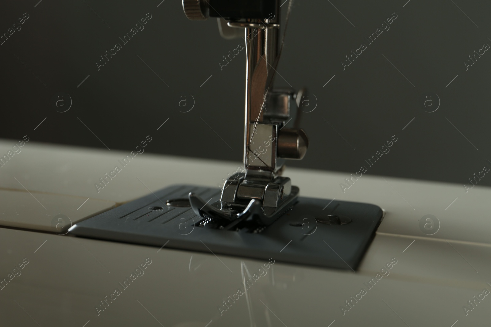 Photo of Modern sewing machine on gray background, closeup