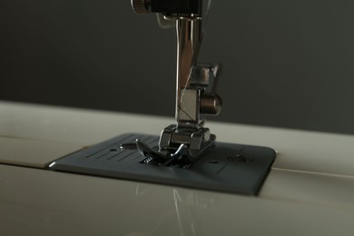 Modern sewing machine on gray background, closeup