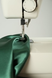 Sewing machine with green fabric on white background, closeup