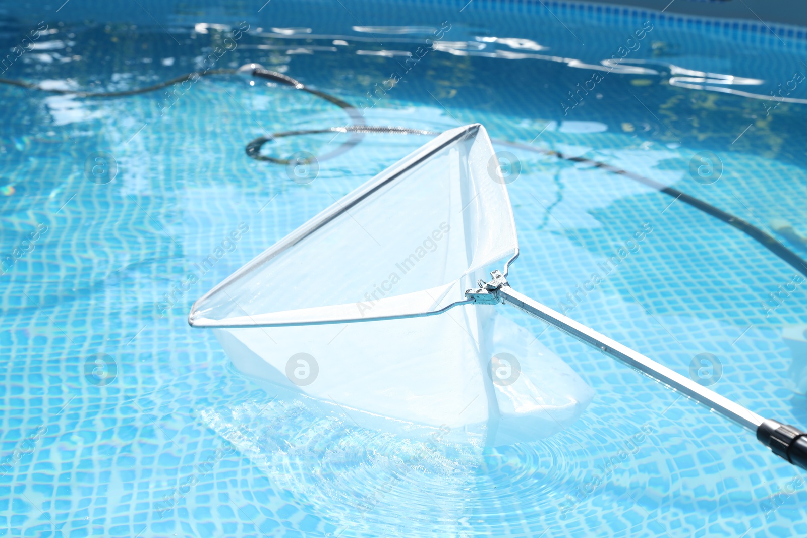 Photo of Cleaning swimming pool with skimmer net, closeup