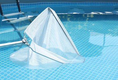 Photo of Cleaning swimming pool with skimmer net, closeup