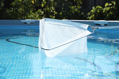 Photo of Cleaning swimming pool with skimmer net, closeup