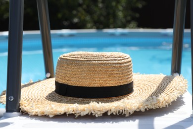 Stylish straw hat near swimming pool outdoors