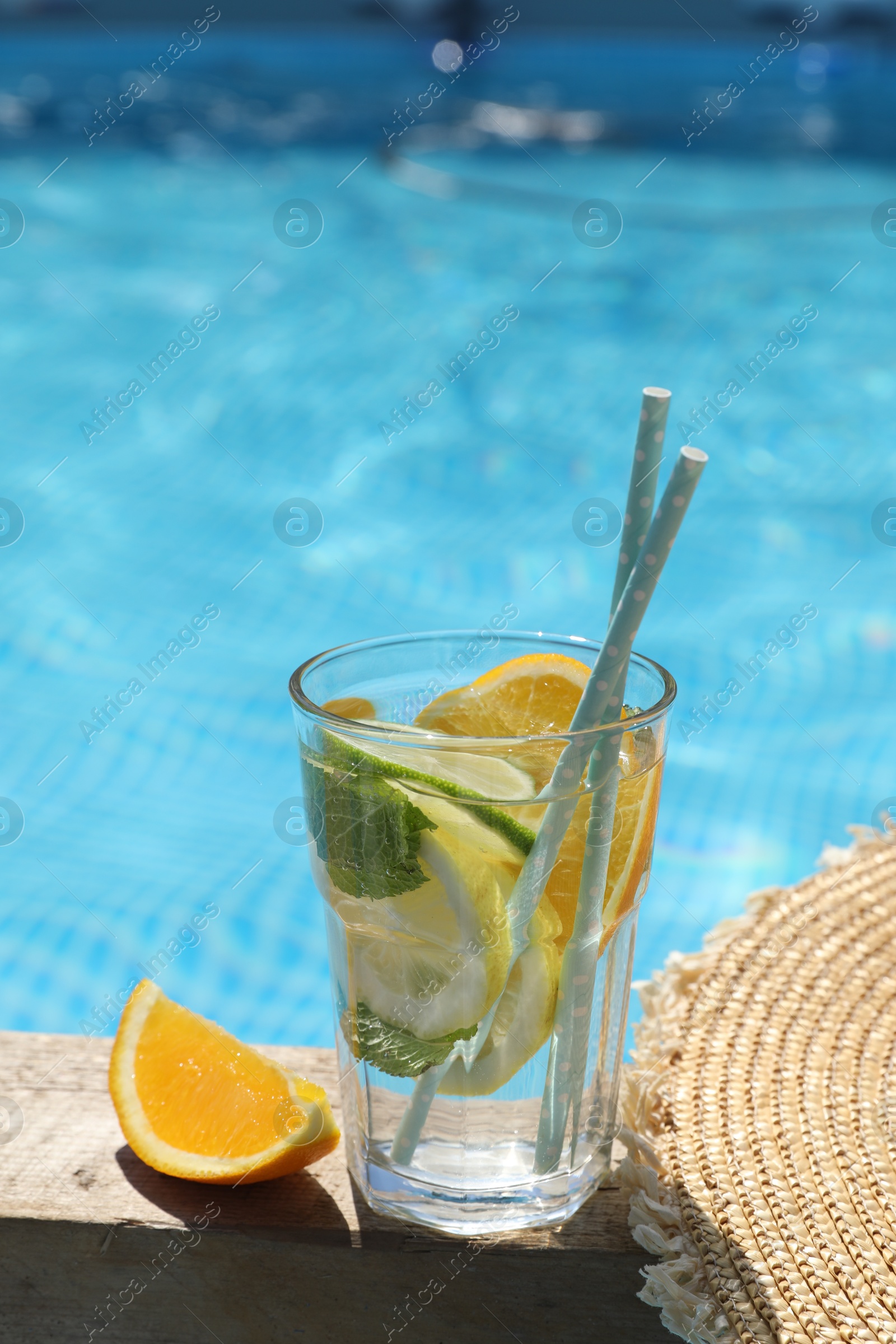 Photo of Tasty cocktail in glass near swimming pool outdoors