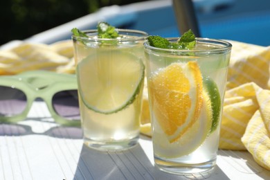 Photo of Tasty cocktail in glasses and sunglasses near swimming pool outdoors