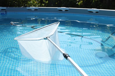 Photo of Cleaning swimming pool with skimmer net, closeup