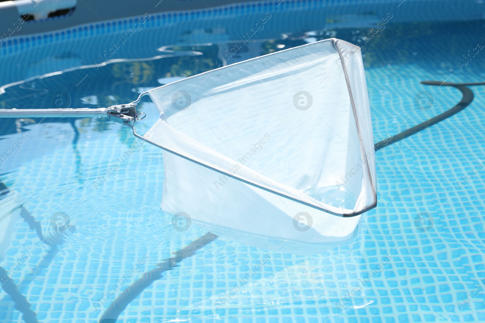 Photo of Cleaning swimming pool with skimmer net, closeup