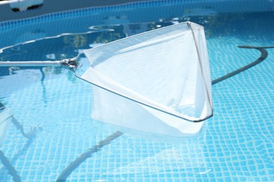 Photo of Cleaning swimming pool with skimmer net, closeup