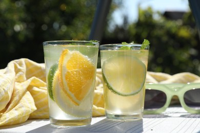 Photo of Tasty cocktail in glasses and sunglasses near swimming pool outdoors