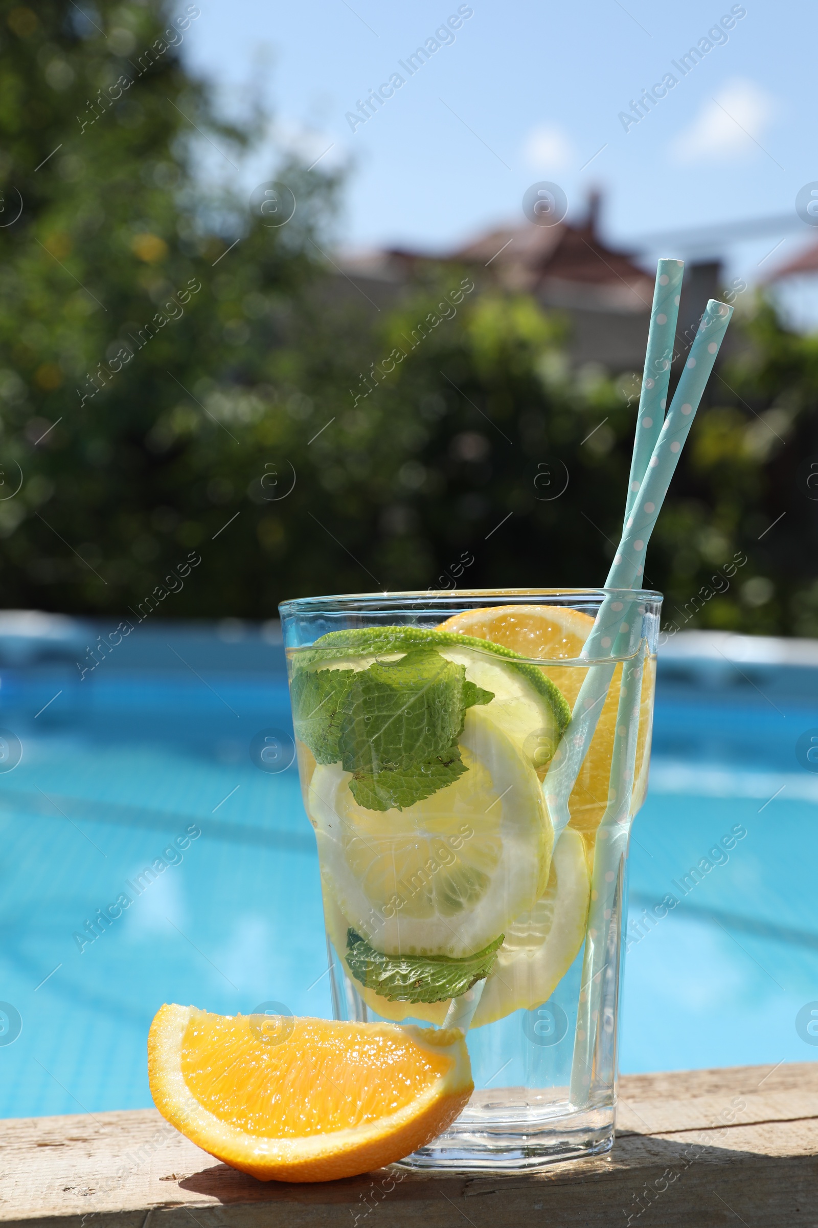 Photo of Tasty cocktail in glass near swimming pool outdoors