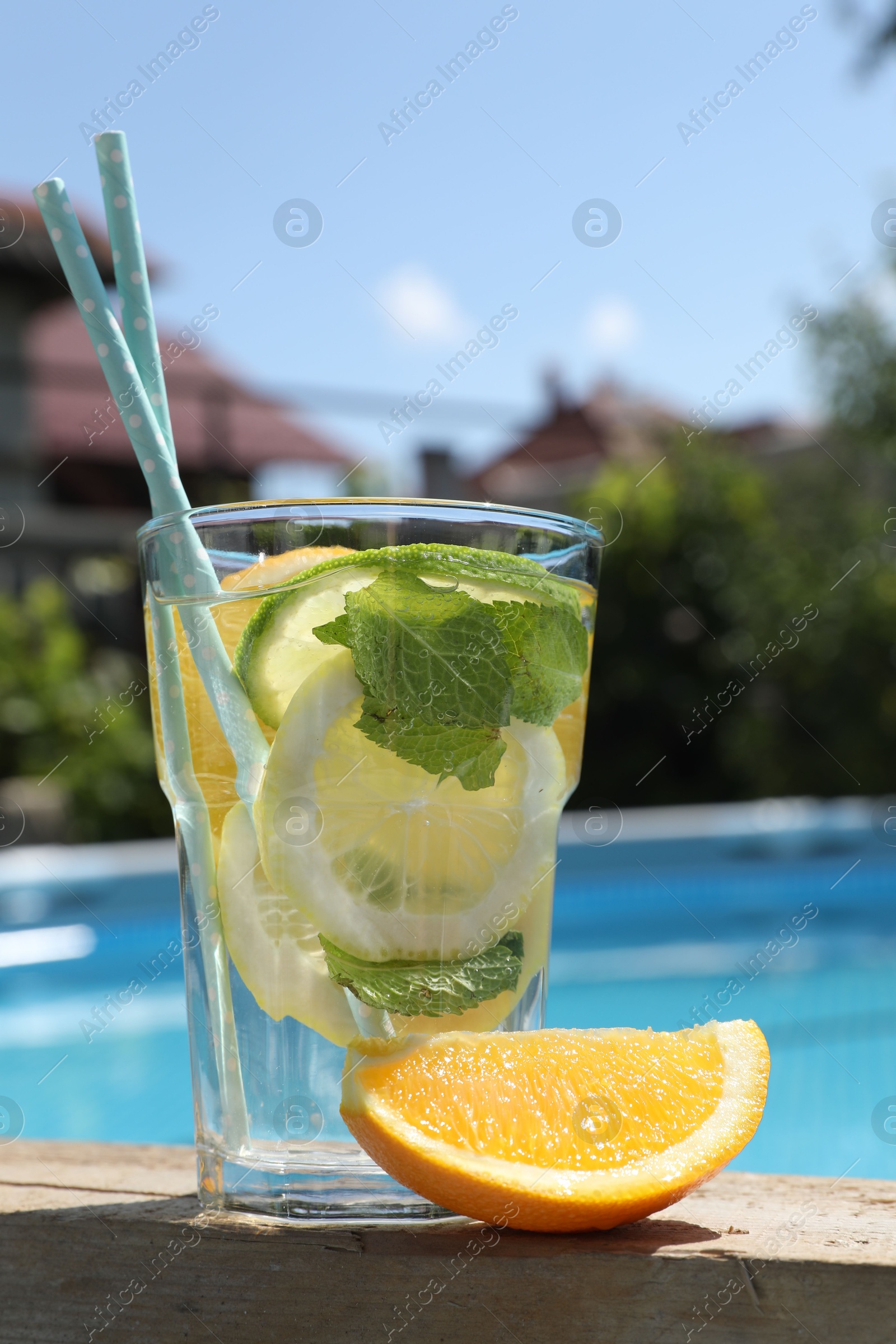 Photo of Tasty cocktail in glass near swimming pool outdoors