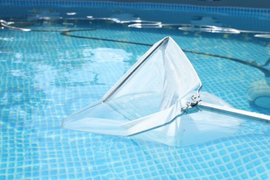 Photo of Cleaning swimming pool with skimmer net, closeup