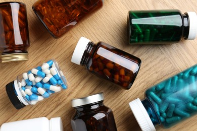 Pharmacist. Different pills in plastic bottles on wooden table, flat lay