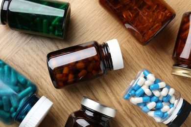 Pharmacist. Different pills in plastic bottles on wooden table, flat lay