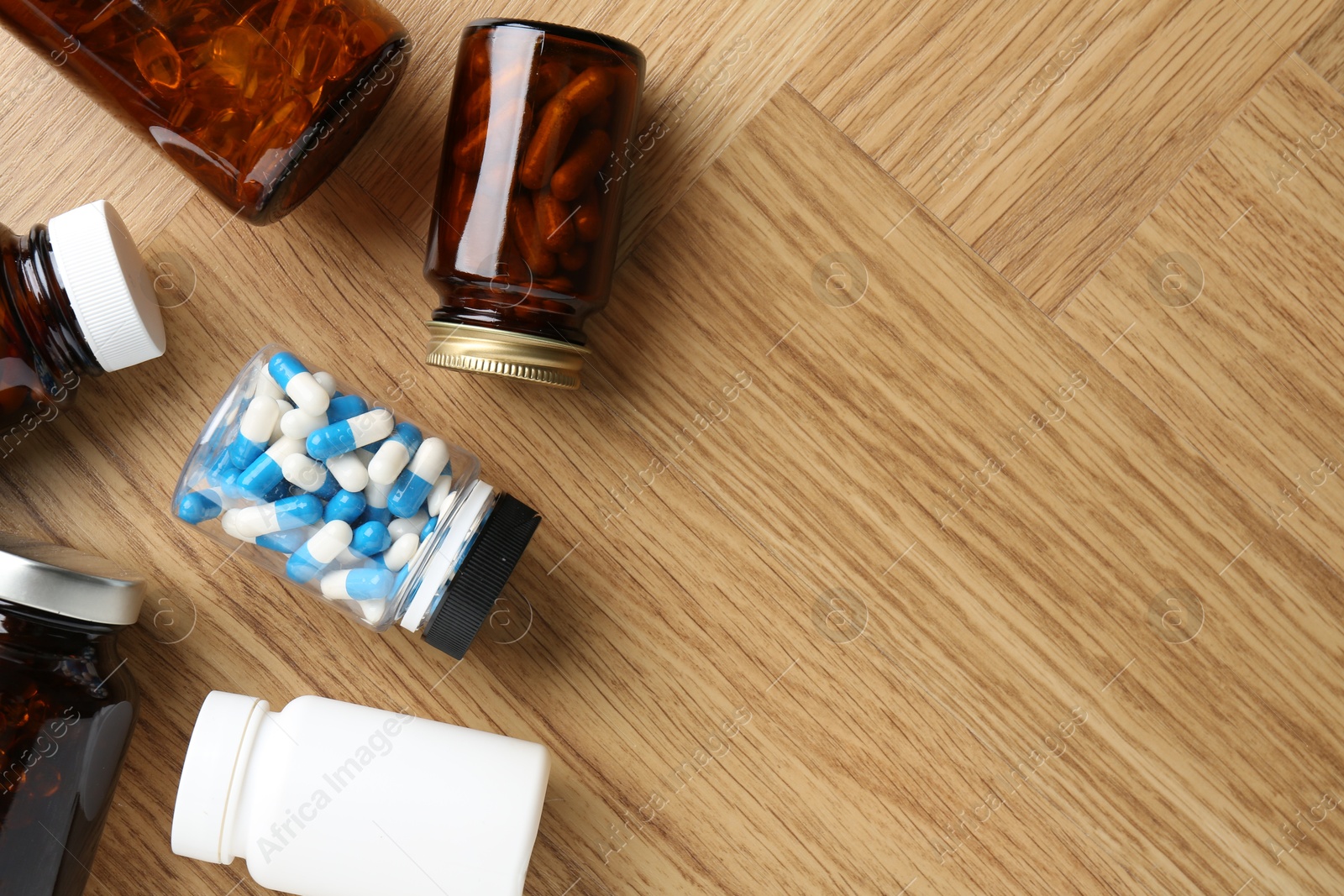 Photo of Pharmacist. Different pills in plastic bottles on wooden table, flat lay. Space for text