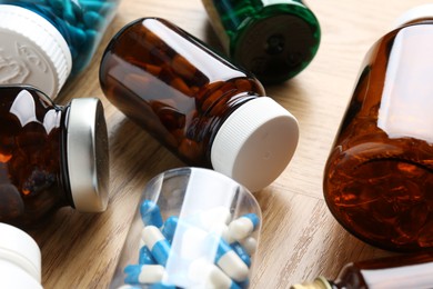 Pharmacist. Different pills in plastic bottles on wooden table, closeup