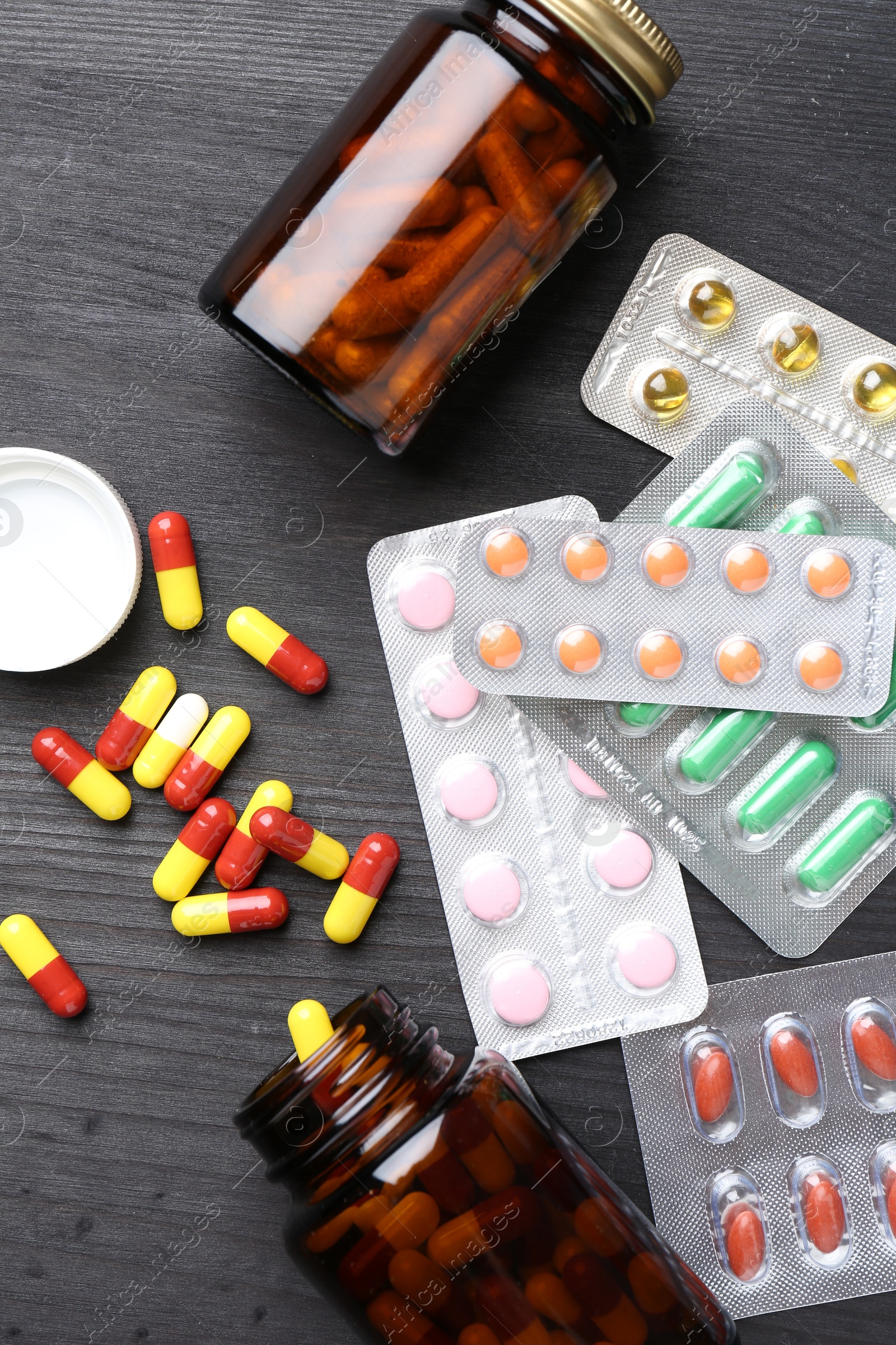 Photo of Pharmacist. Different pills and plastic bottles on grey wooden table, flat lay