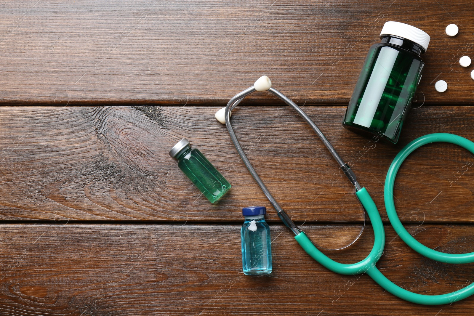 Photo of Pharmacist. Glass vials, stethoscope, bottle and pills on wooden table, flat lay. Space for text